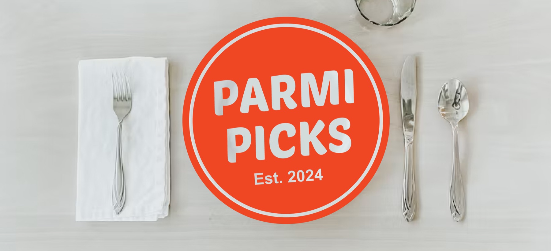 Parmi Picks logo badge centred on a laid table setting with napkin, cutlery and a glass